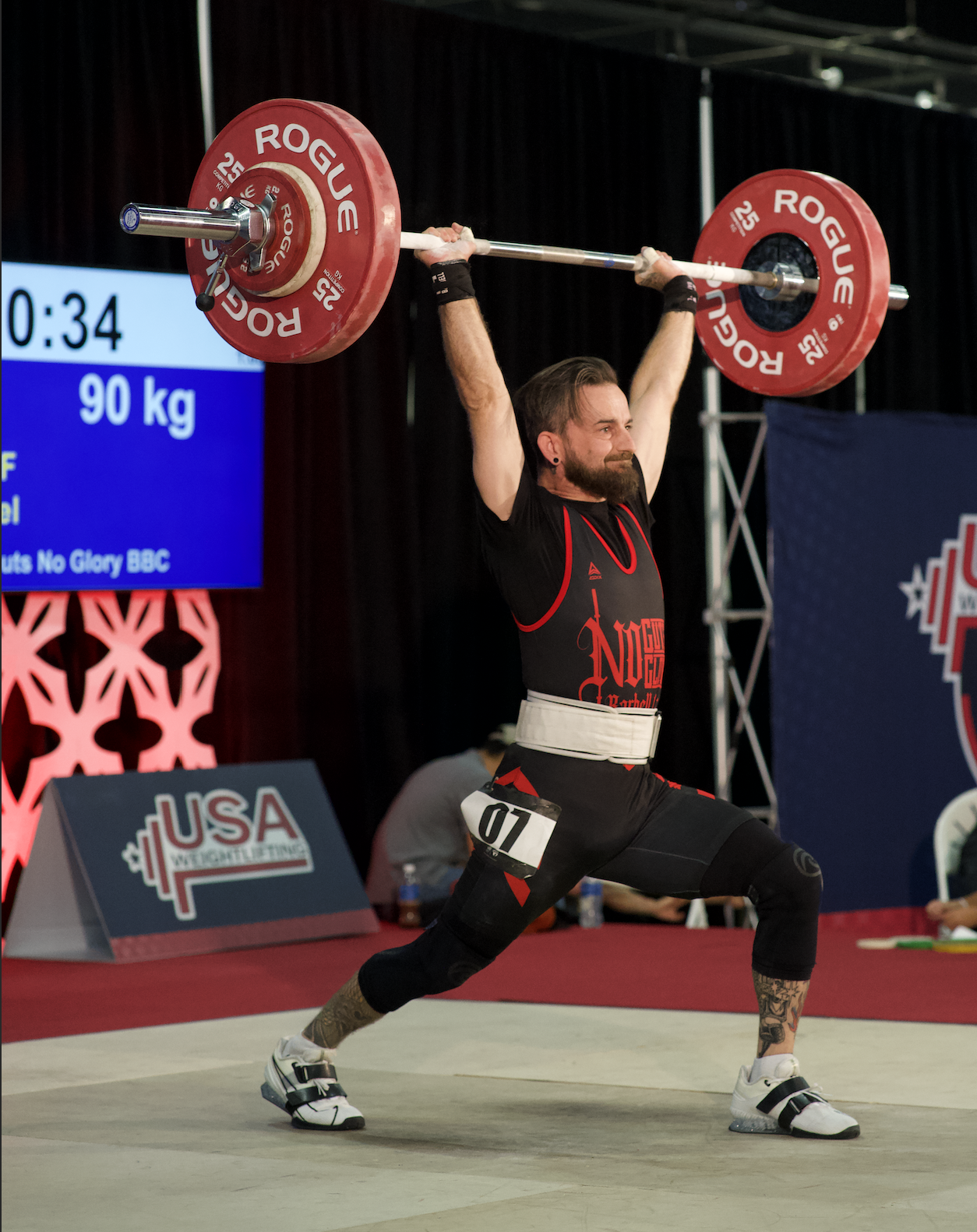 A man is lifting a barbell in front of a usa sign