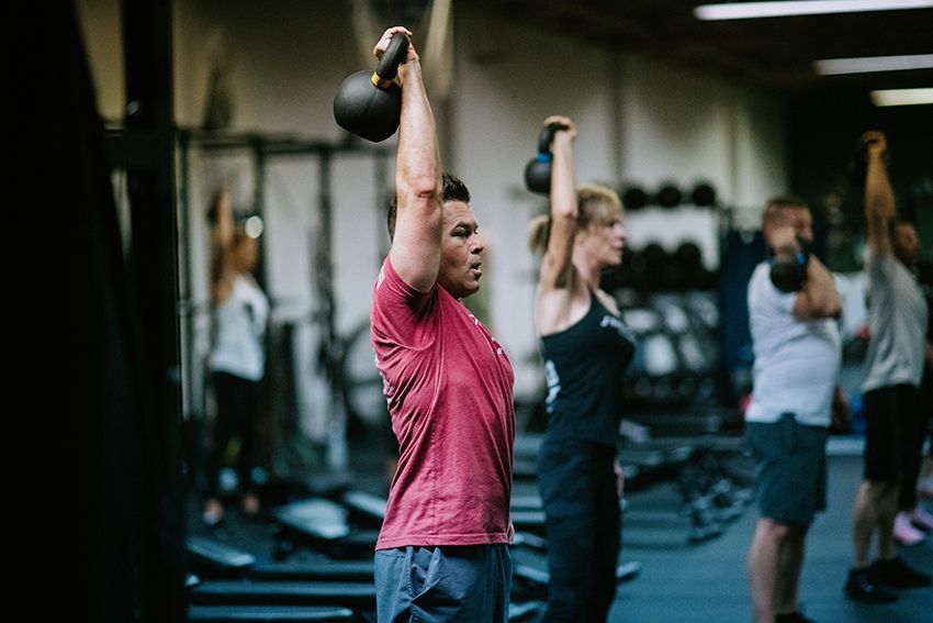 A group of people are lifting kettlebells in a gym.