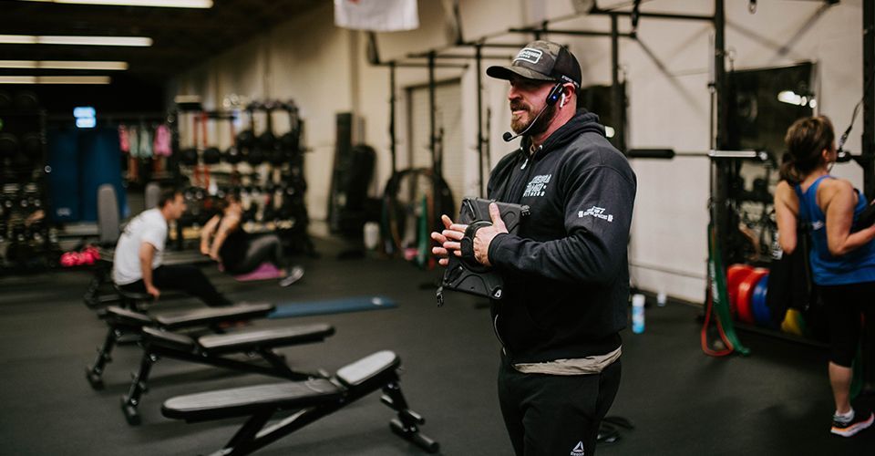 A man is standing in a gym talking on a cell phone.