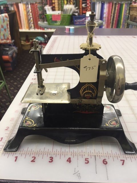 Antique black and gold sewing machine with a hand crank on a table.