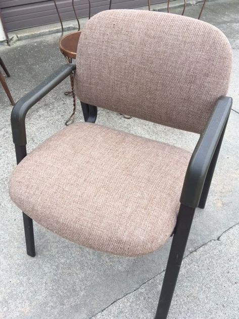 Brown upholstered office chair with black arms and legs, set outside on concrete.
