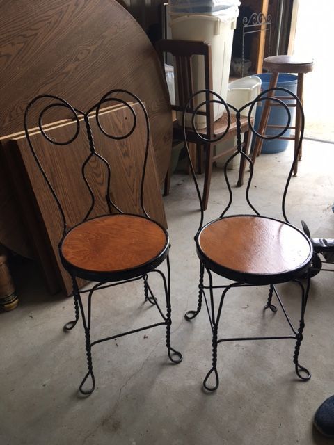 Two black wrought iron chairs with circular wooden seats.