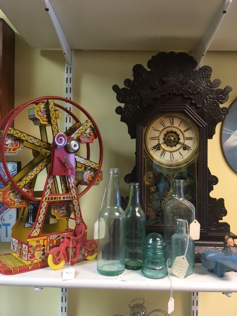 Antique shelf with a Ferris wheel toy, bottles, and a clock.