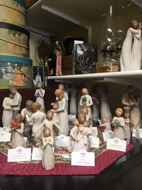 Display of Willow Tree figurines on a shelf, featuring neutral colors, depicting various embracing figures.