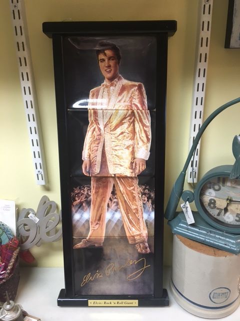 Elvis Presley portrait in gold suit, framed in black, in a store.