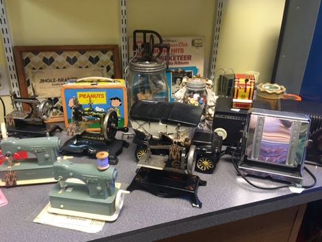 Collection of vintage toys and appliances, including sewing machines, a toaster, and a Peanuts lunchbox.