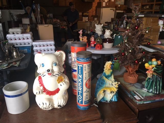 A collection of vintage items: bear figurine, TinkerToy cylinder, nativity scene, and a small Christmas tree.