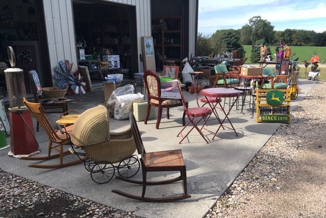 Outdoor garage sale; furniture, decor, and antiques displayed on a concrete slab.