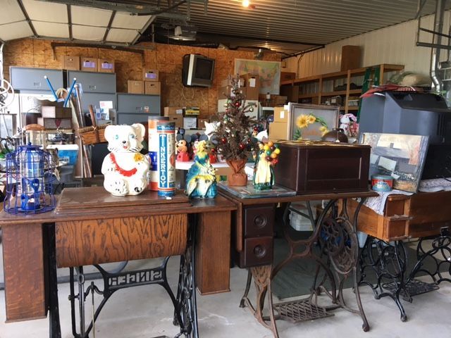 Garage filled with vintage items: sewing machines, art, figurines, and electronics.