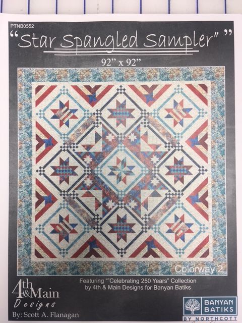 Quilts displayed on a yellow wall with a wooden chair and cabinet; a small doorway is to the right.