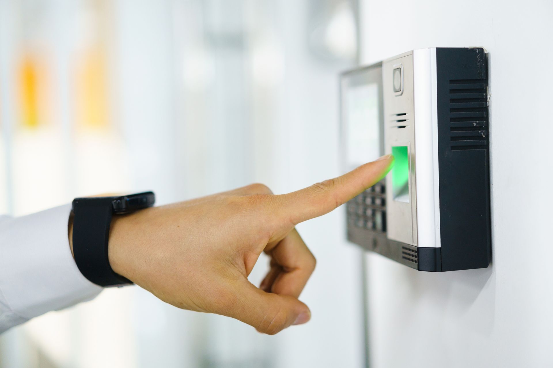 A person is pressing a button on a fingerprint scanner.