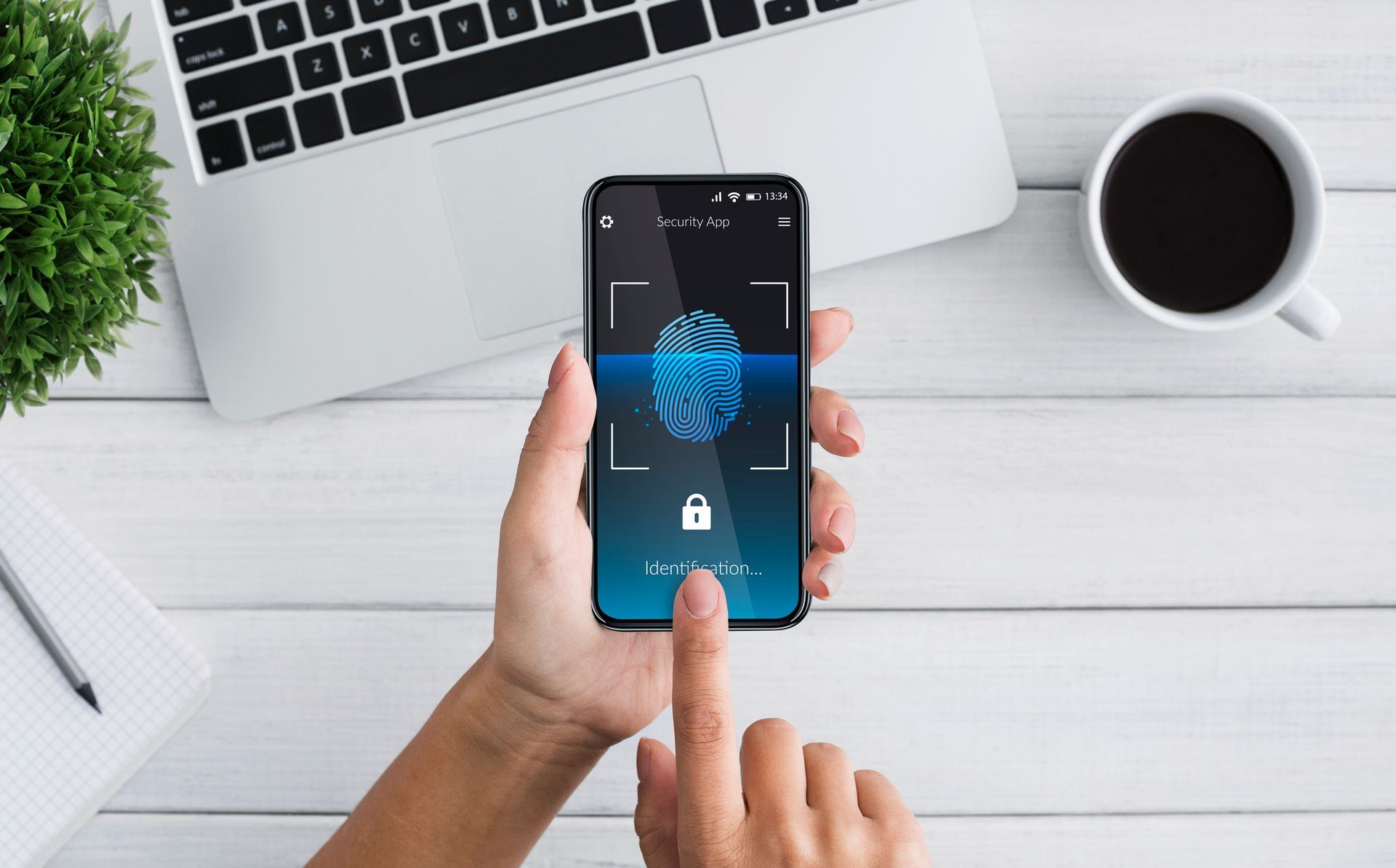 A person is holding a cell phone with a fingerprint scanner on it.