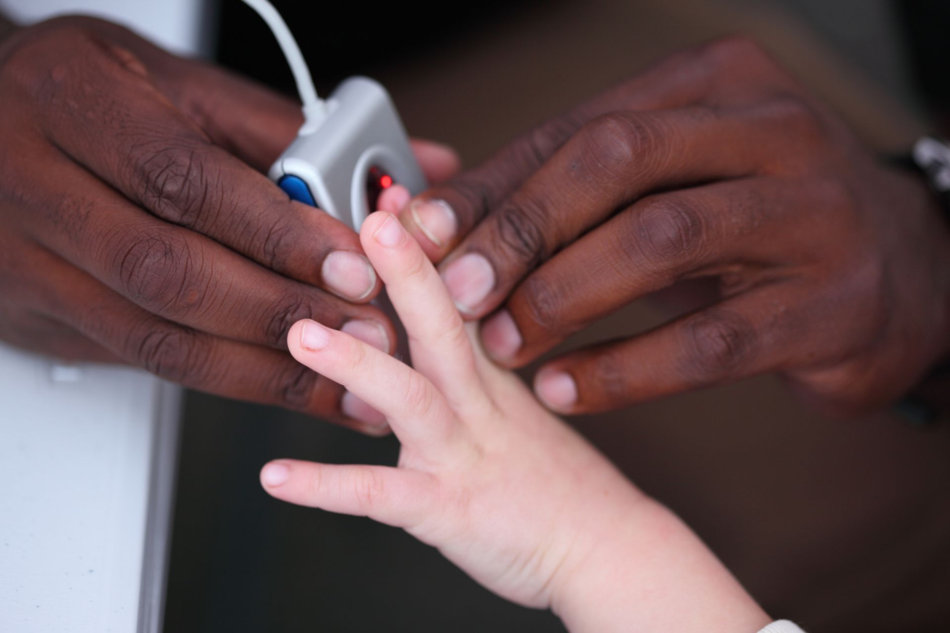 A person is using a fingerprint scanner on a child 's finger