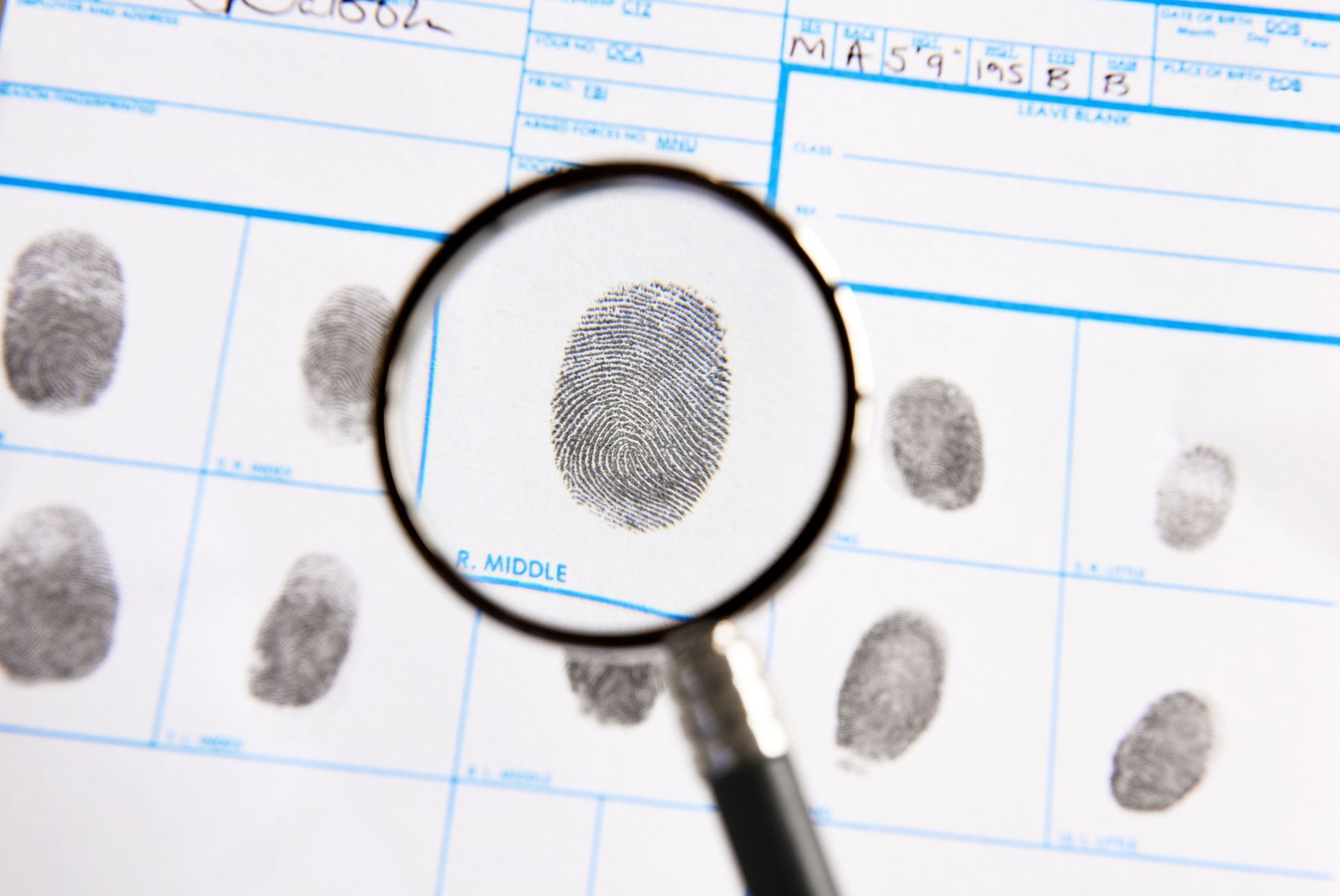 A magnifying glass is looking at a fingerprint on a piece of paper.