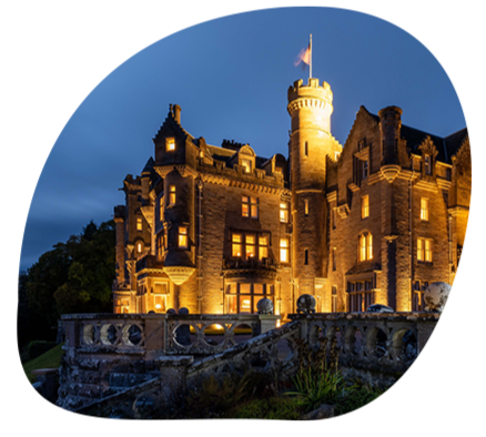 A castle is lit up at night and surrounded by water