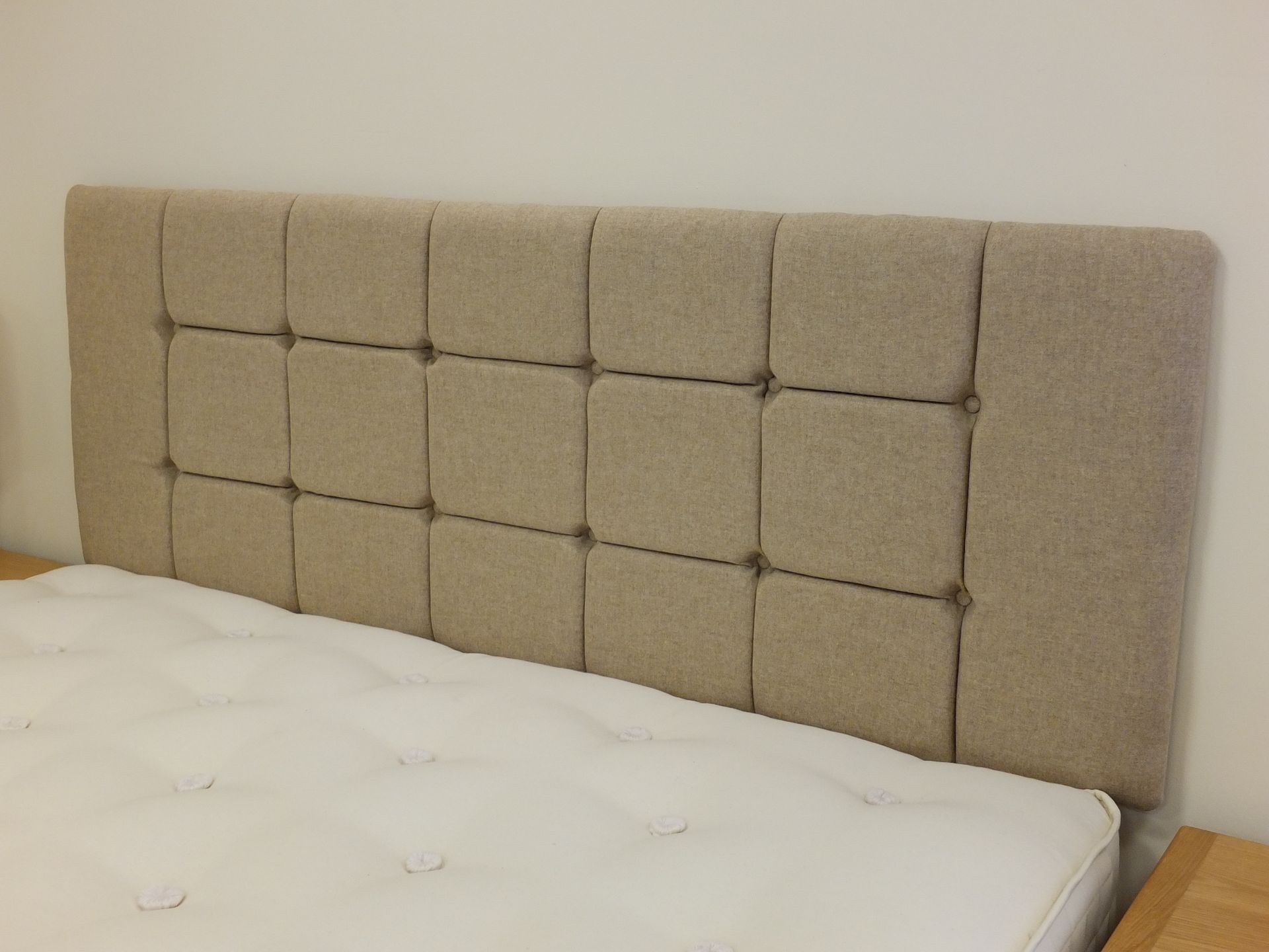 A bed with a beige headboard and a white mattress