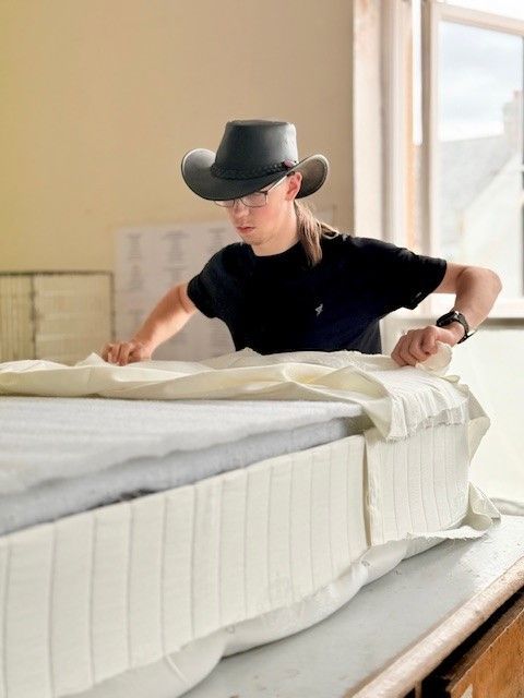 Josh, an emloyee a Hghland BlindCraft works on a mattress.
