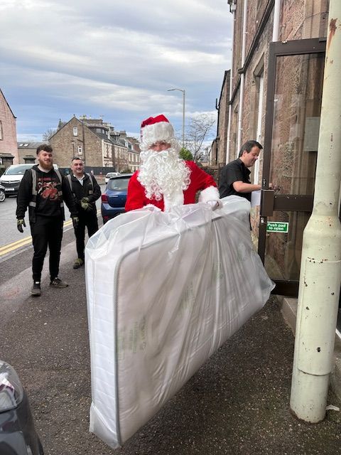 Santa is outside helping with a Highland BlindCraft Beds delivery