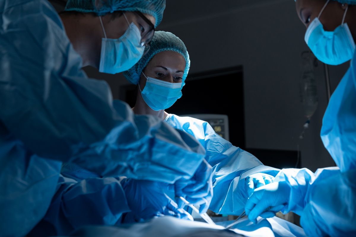 A group of surgeons are operating on a patient in an operating room.