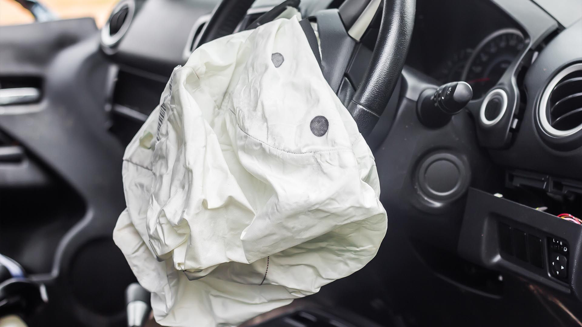 An airbag is hanging from the steering wheel of a car.