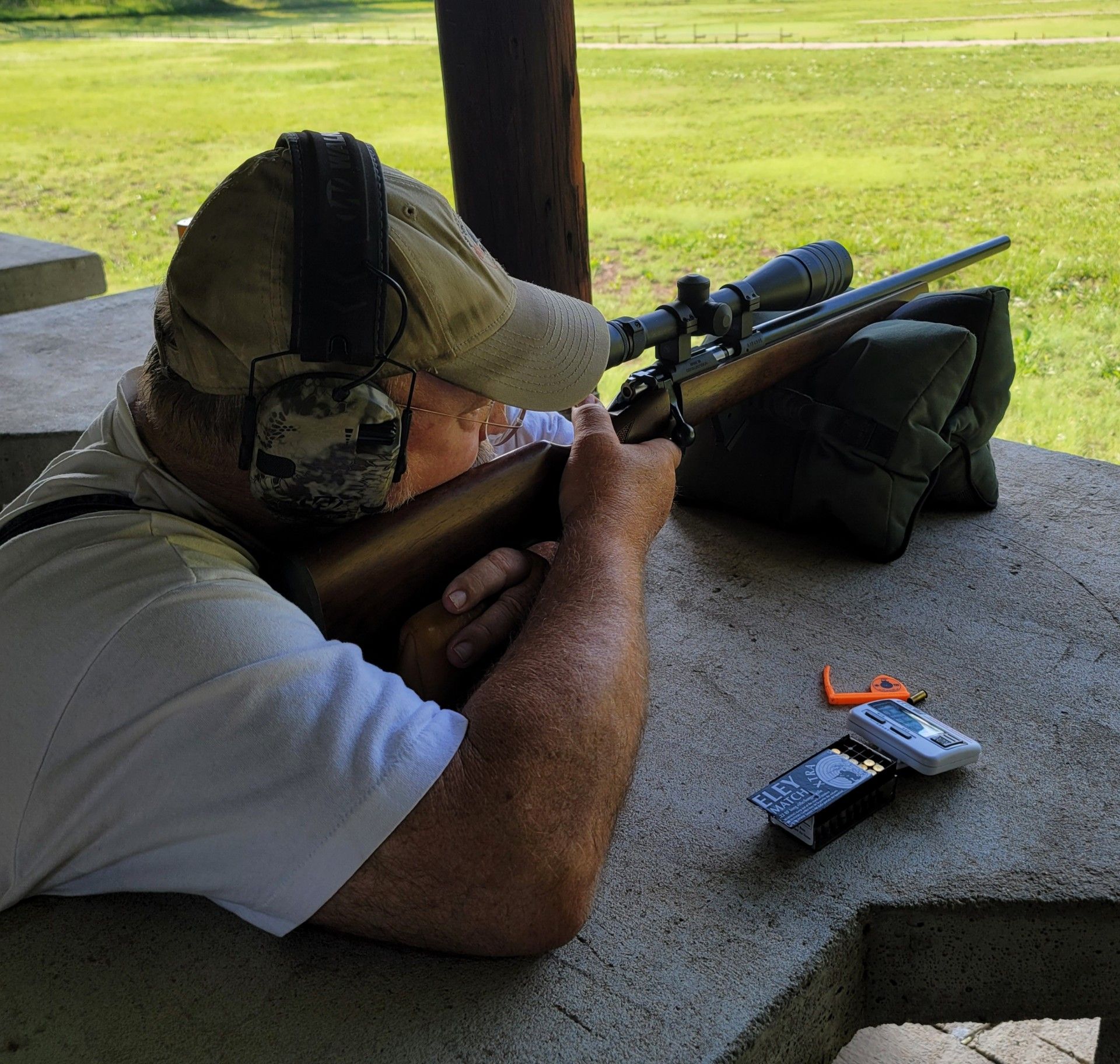 man wearing ear protection while shooting a rifle at gun range table