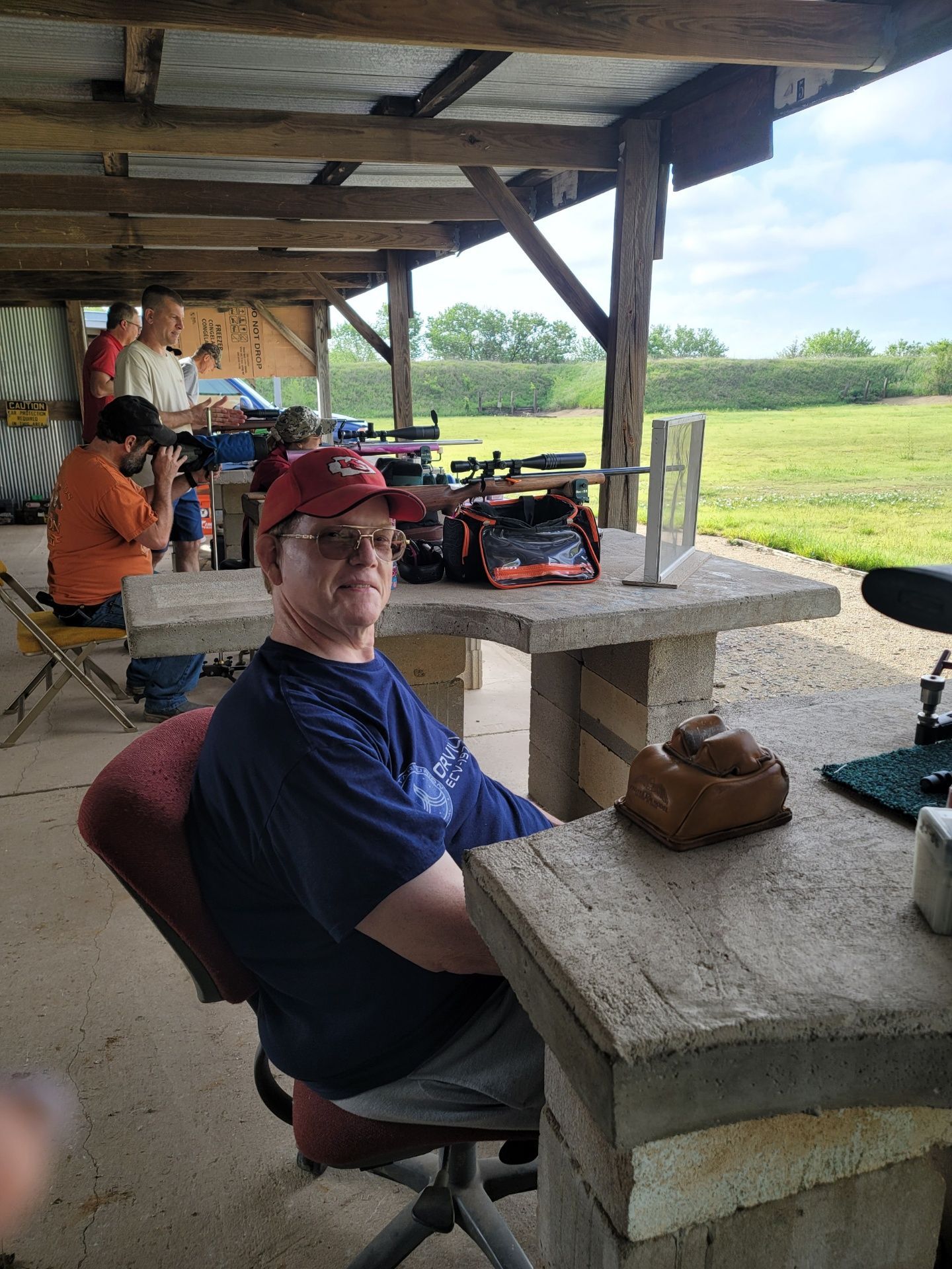 a man wearing a blue shirt that says texas on it sitting at gun range table