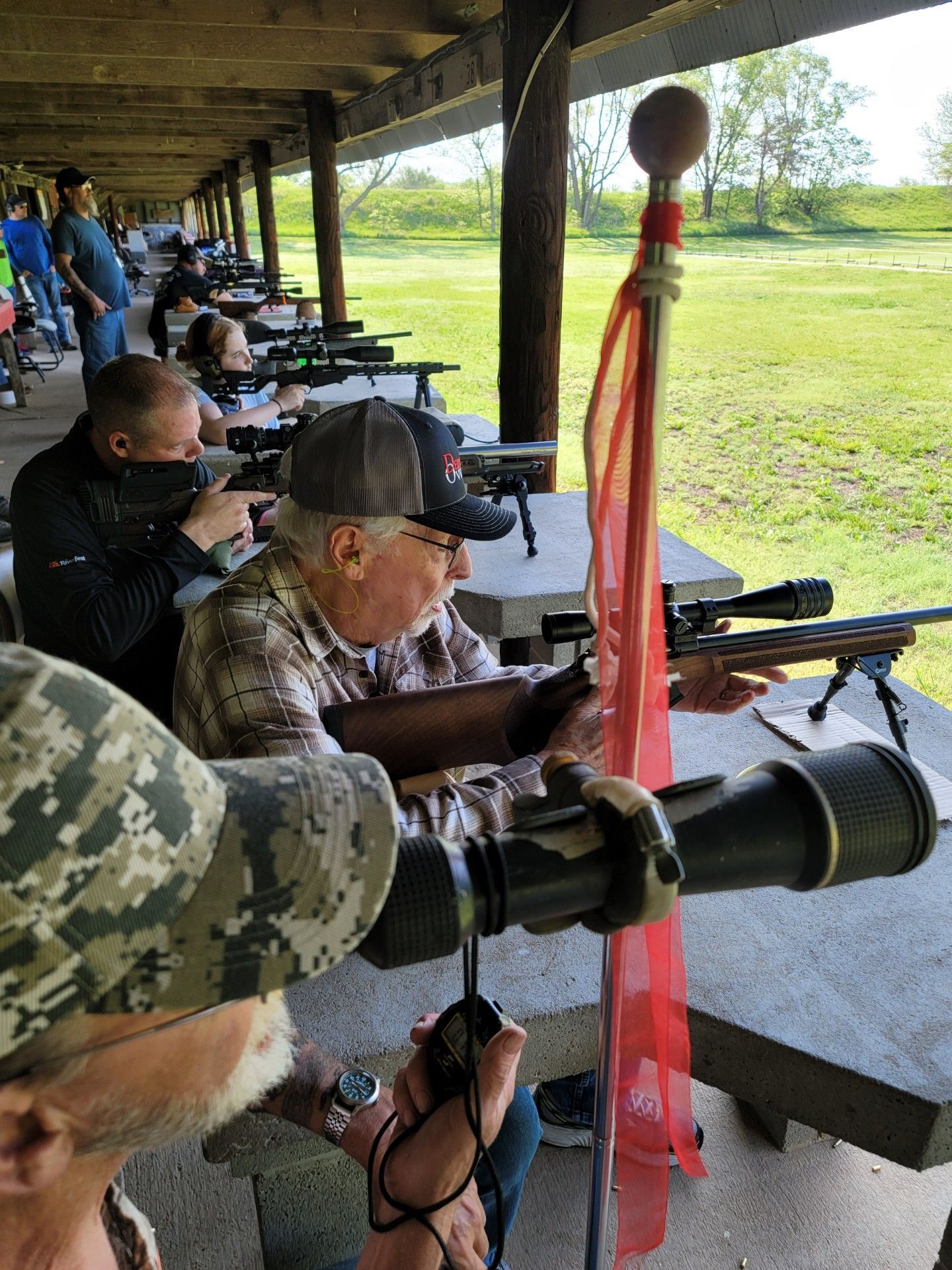 looking down line of men and young people shooting rifles at gun range