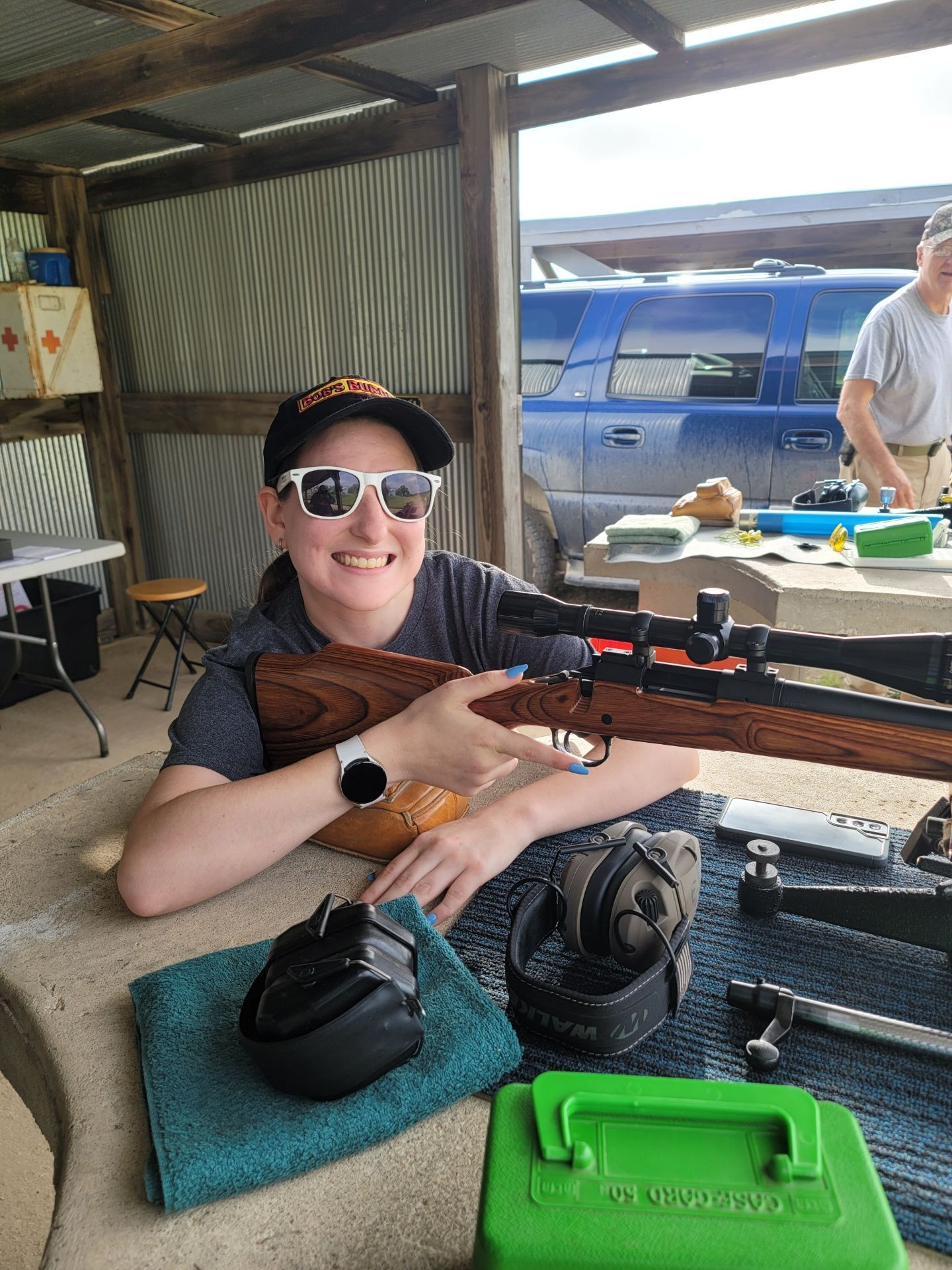 boy wearing sunglasses holding a rifle at shooting range