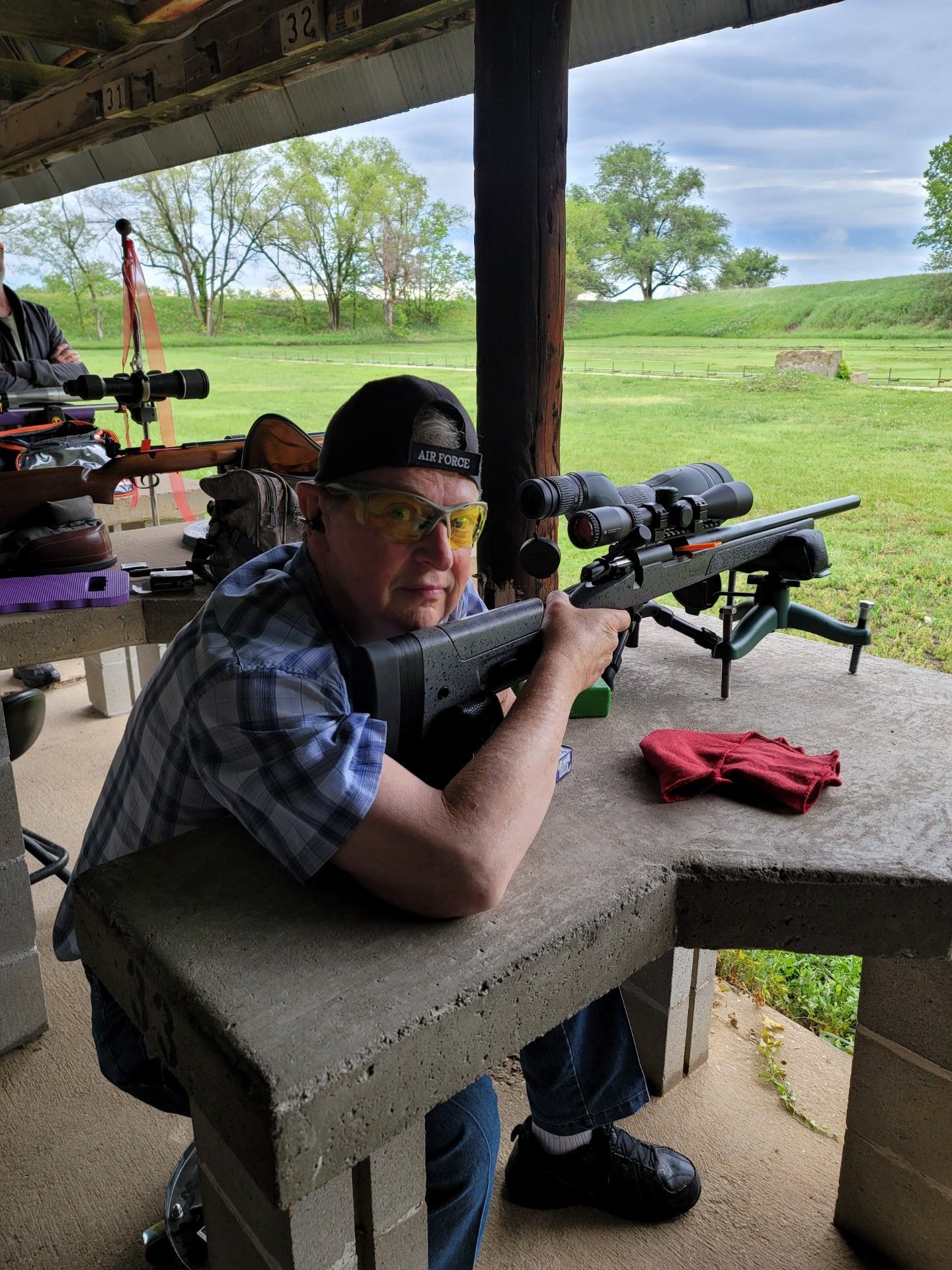 man in safety glasses posing with rifle at gun range