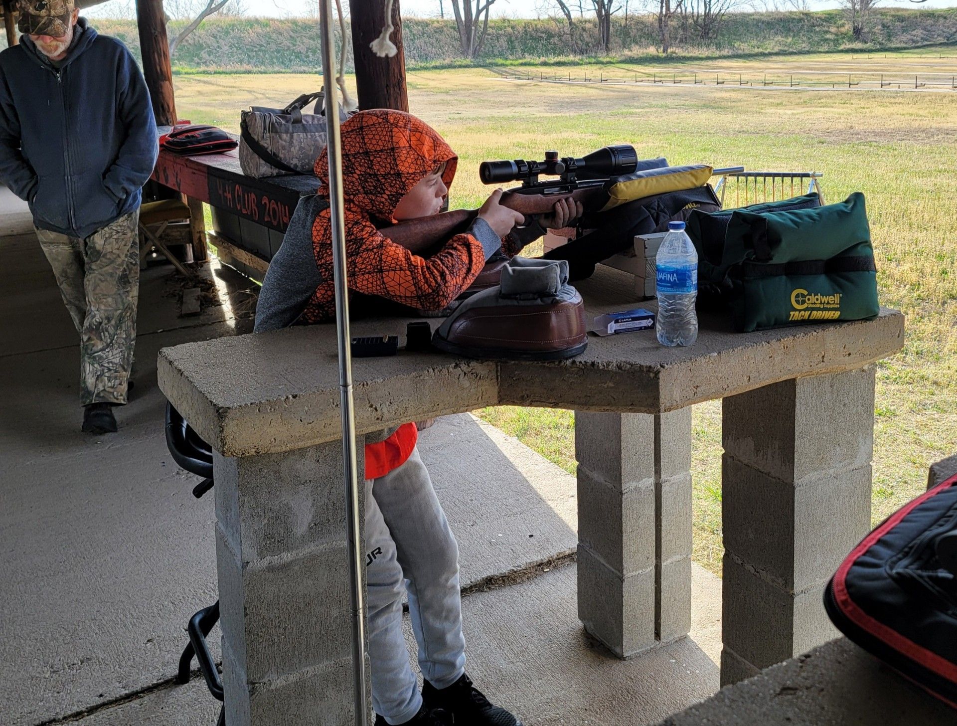 young boy taking aim with a rifle at gun range table