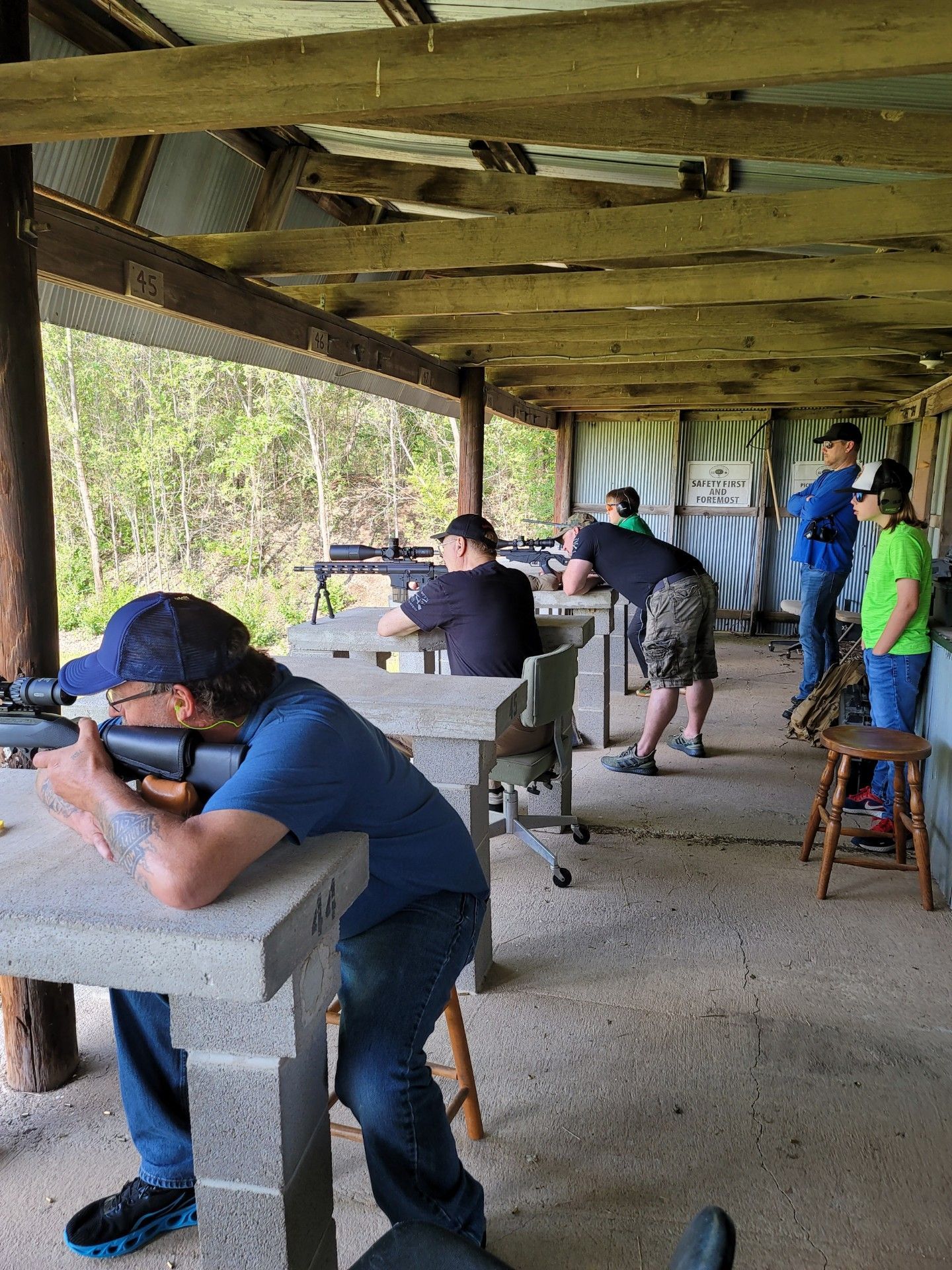 several men at gun range line holding rifles aimed down range