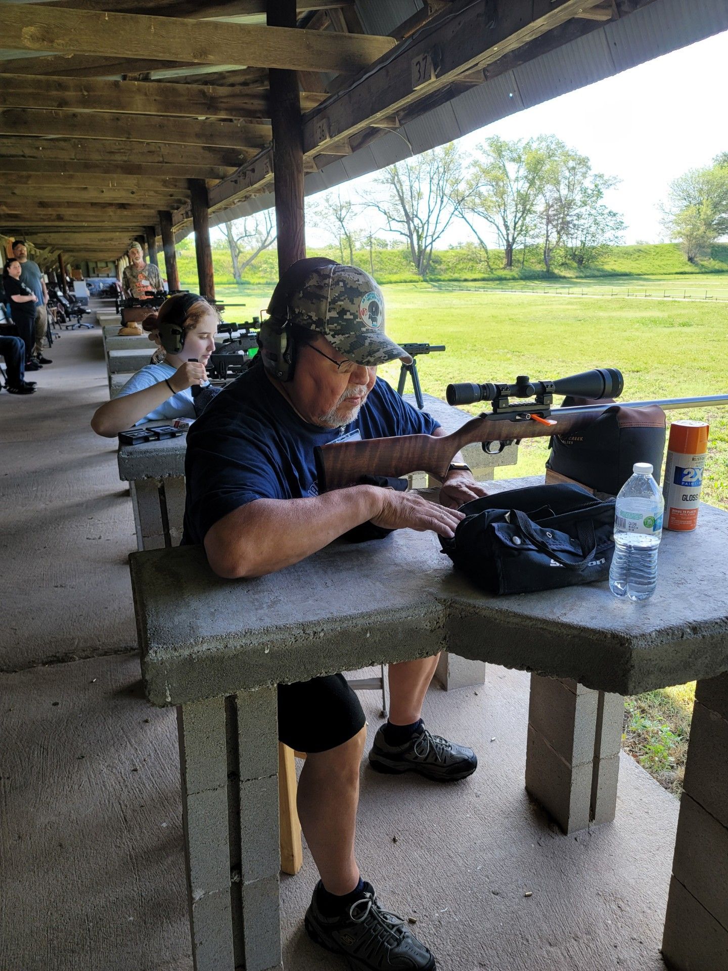 man in camouflage hat looking in ammo bag at rifle range