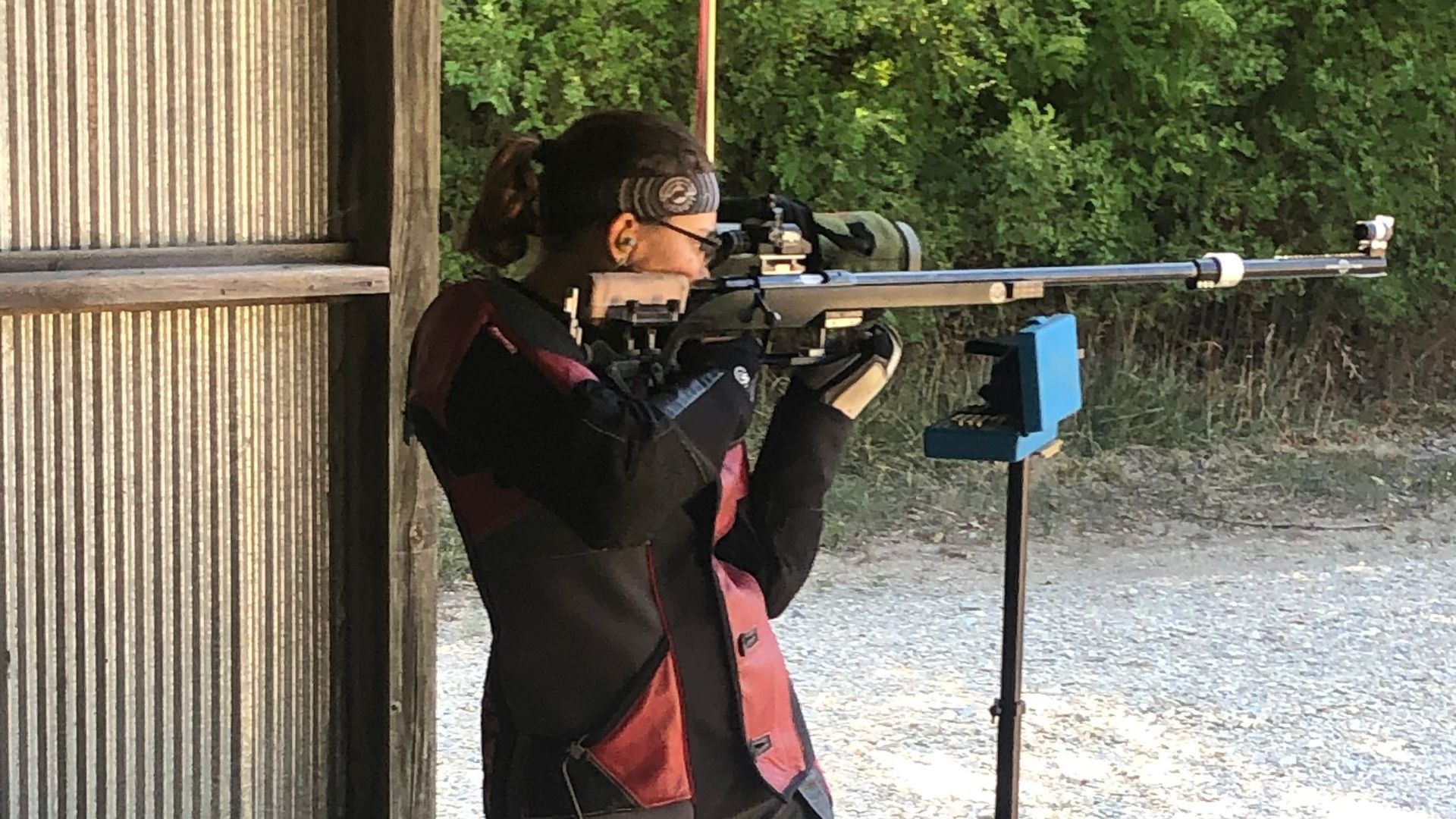 woman taking aim with a rifle standing at gun range