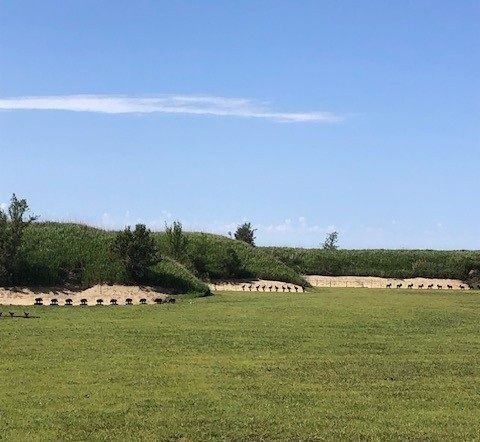 woman taking aim with a rifle while leaning on table at gun range