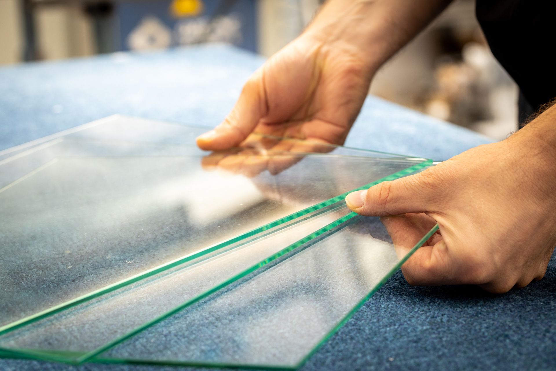 A person is measuring a piece of glass with a tape measure.