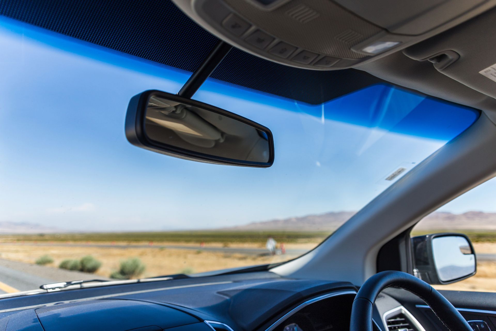 The inside of a car with a rear view mirror and windshield.