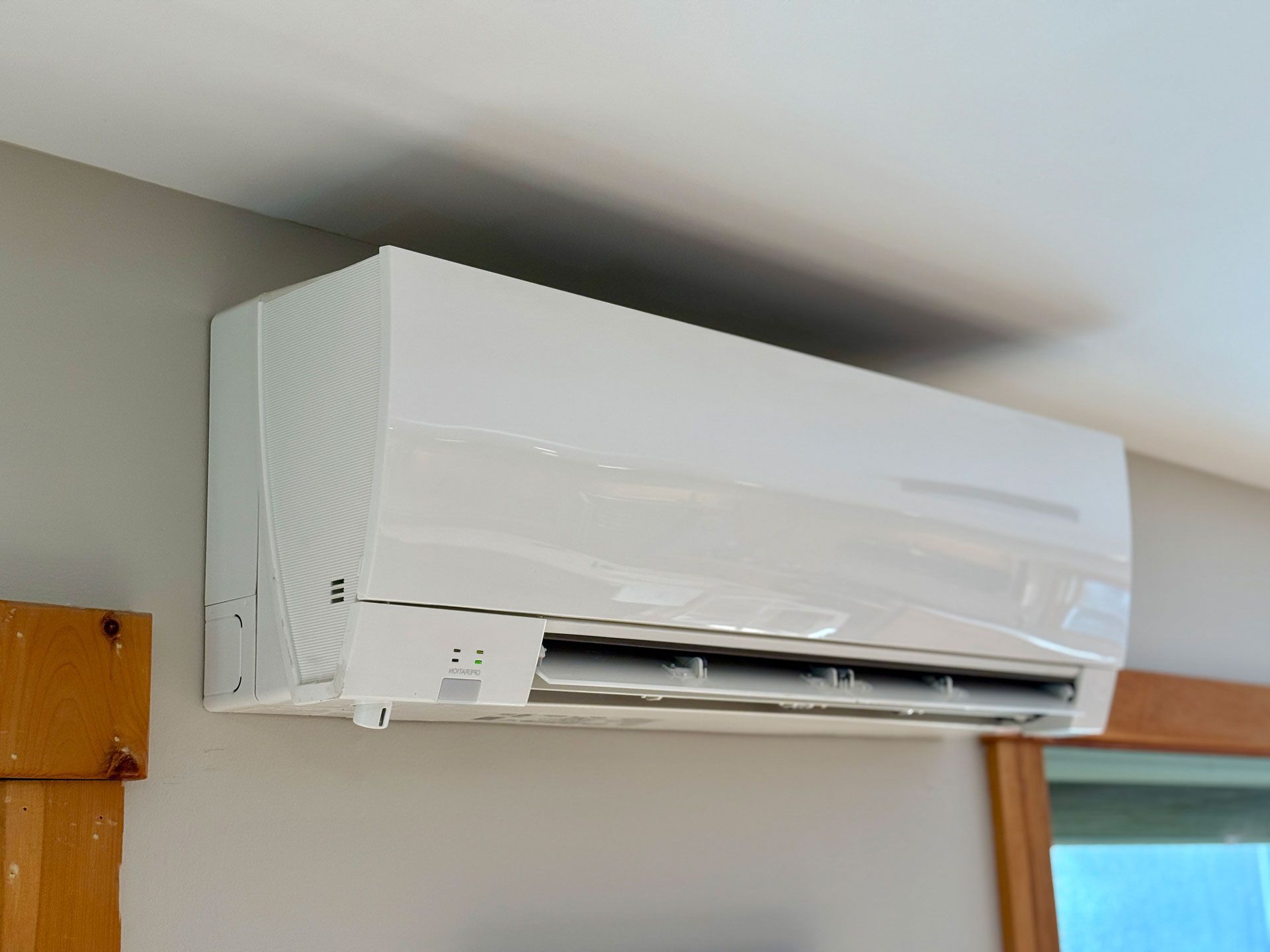 A white air conditioner is hanging from the ceiling in a room.