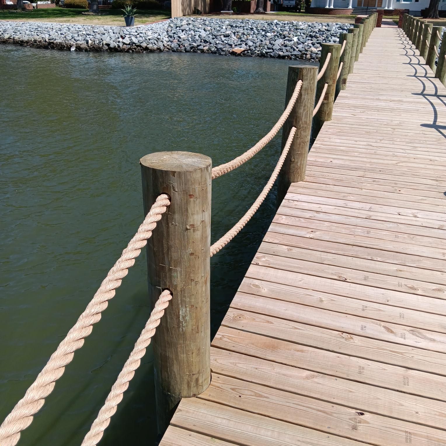 Wooden pier with rope railing extending into water.