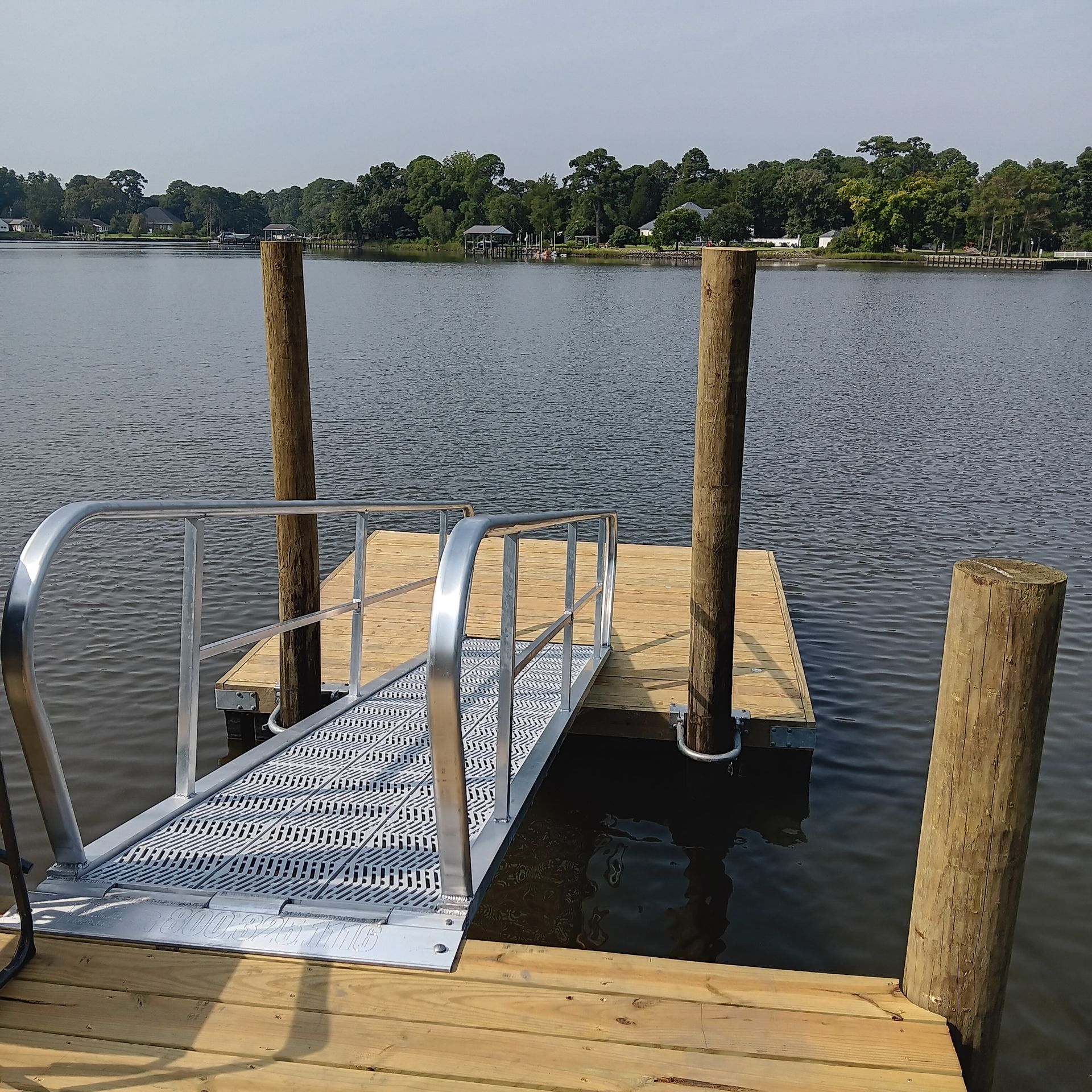 Blue fishing boat on water with net structure under cloudy sky.