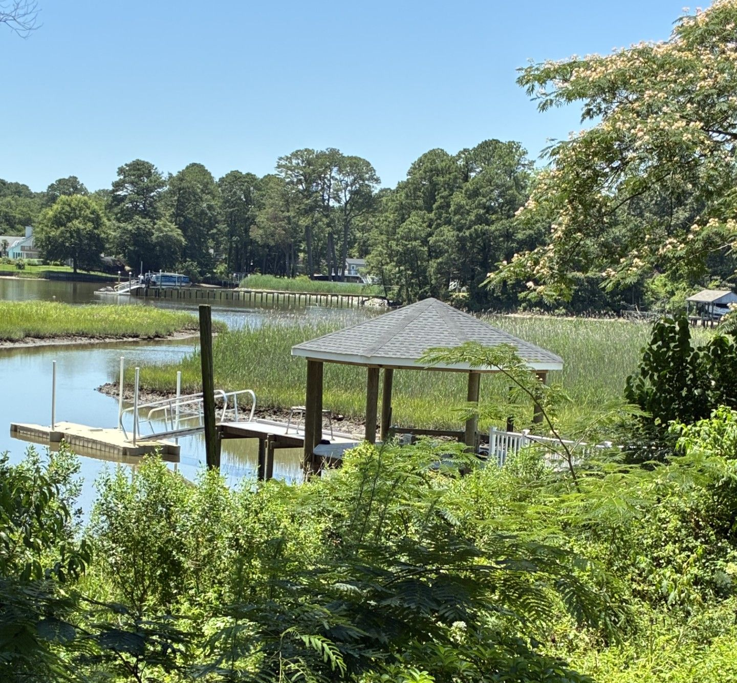 Wooden pier over turquoise water with a thatched roof structure on the left under a blue sky.