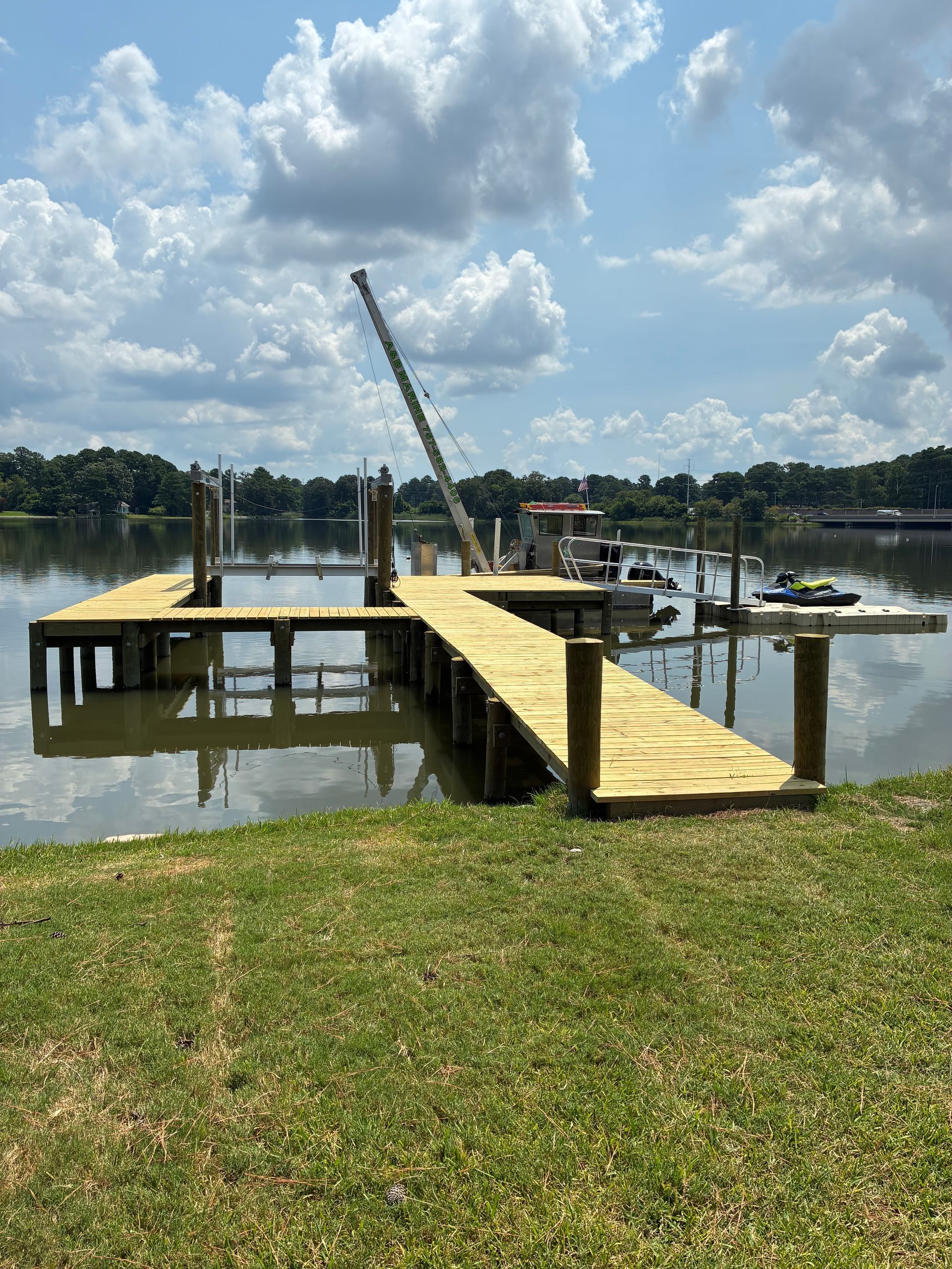 Gondolier in straw hat and red scarf stands by his black gondola in a canal, Venice.