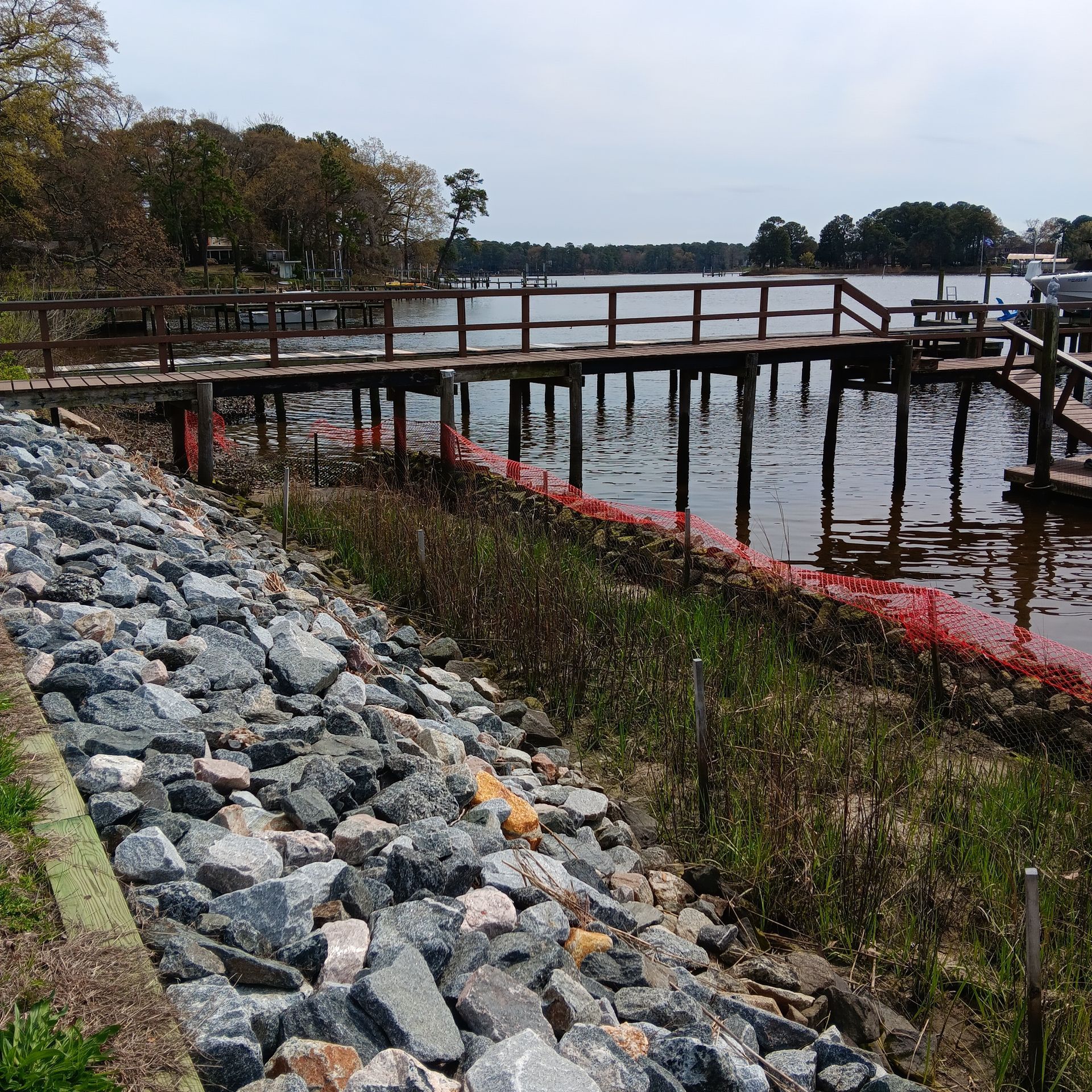 Wooden dock and retaining wall by a house on a lake.