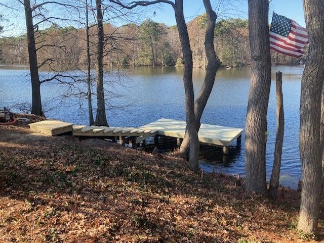 Wooden dock extending over murky water. Metal railing and ramp leading to a second dock section.