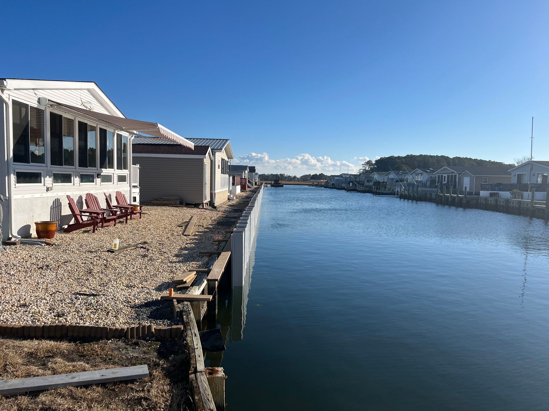 Harbor scene: cranes of various colors by water under a blue sky.
