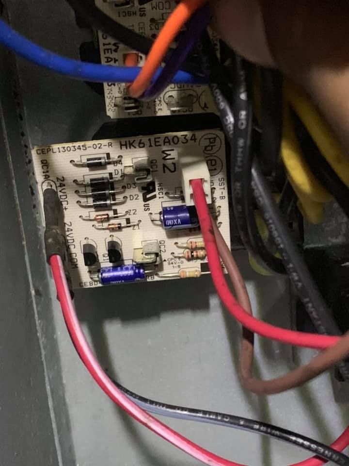 A circuit board labeled HK61EA034 with various wires connected to it, located inside an electrical or HVAC enclosure.