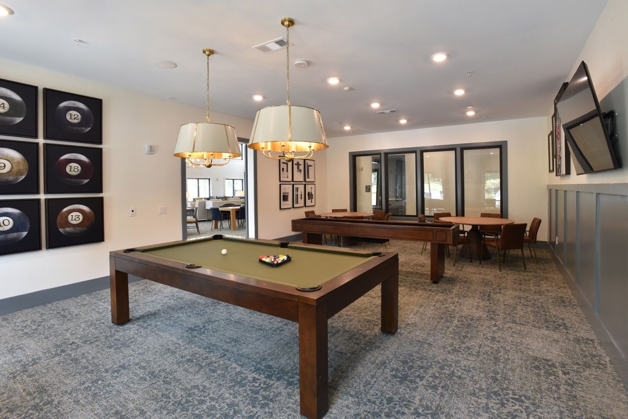 Indoor community recreation room featuring a pool table, seating, and a wall-mounted TV.