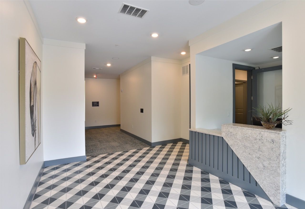Interior view of a modern apartment lobby with geometric tile floor and marble front desk.