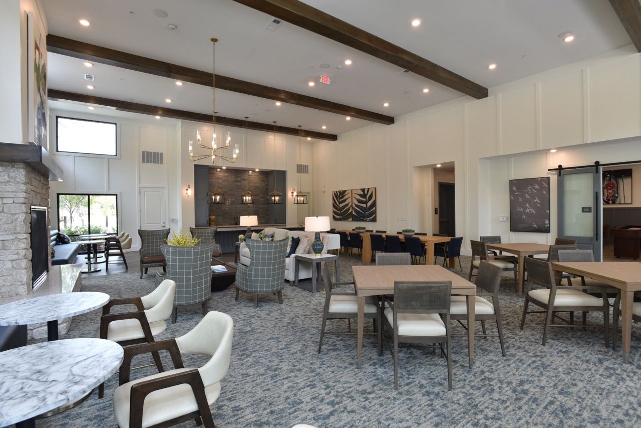 Spacious apartment community lounge with seating areas, tables, and a stone fireplace.