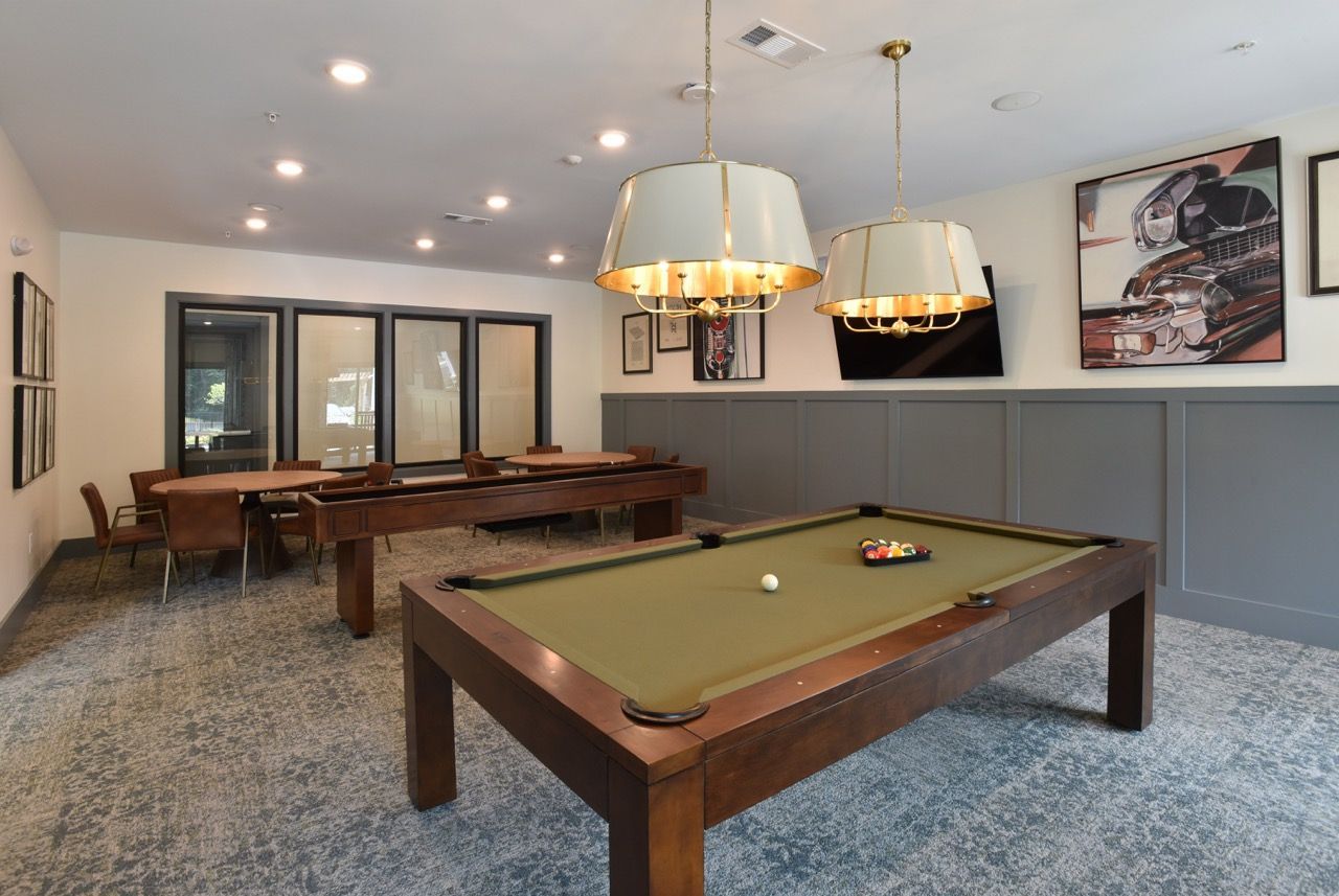 Indoor community recreation room with pool table, seating, and wall art.
