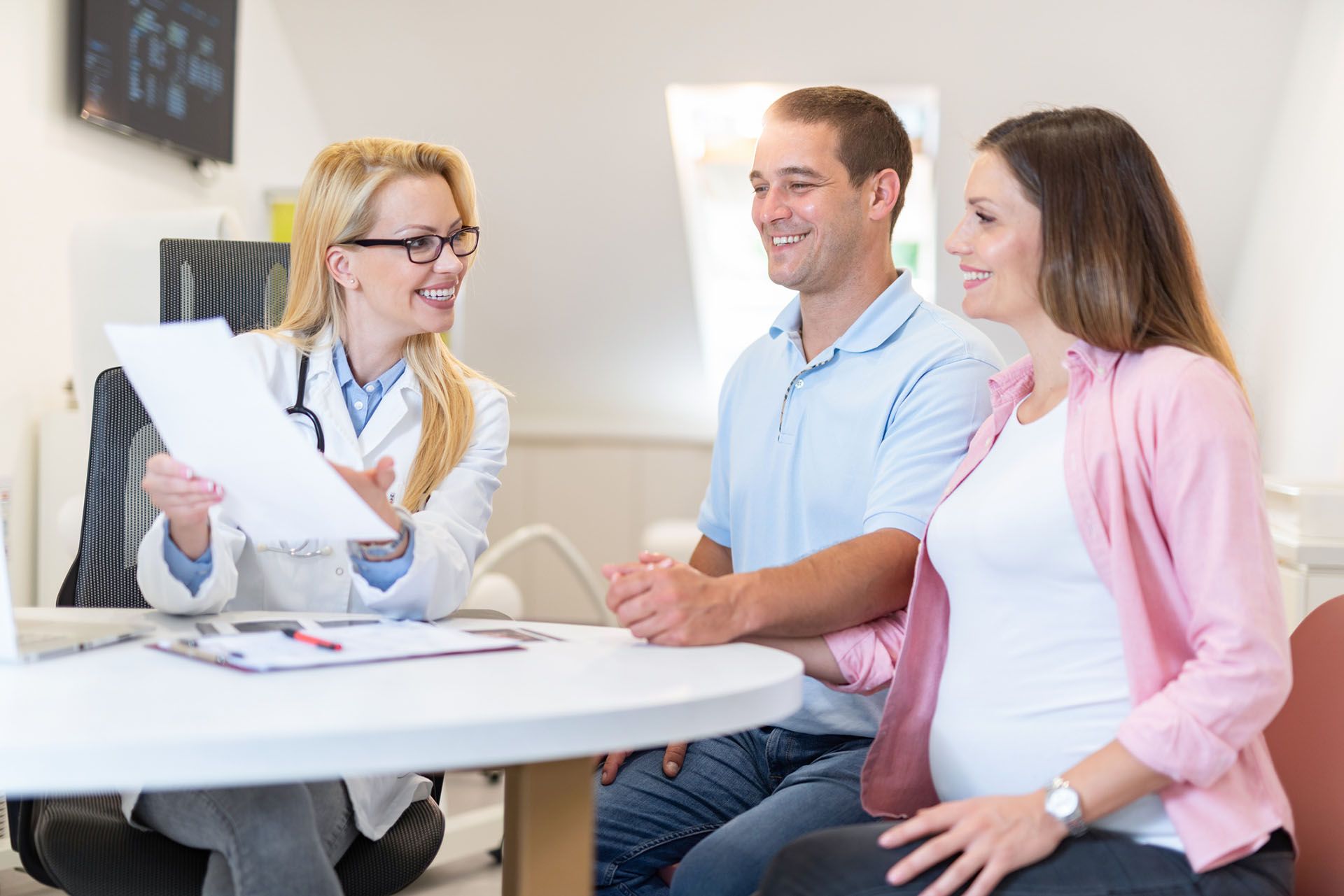 A pregnant woman and a man are sitting at a table talking to a doctor
